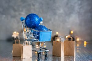 Holiday shopping. Shopping cart with blue shiny balls and paper bags